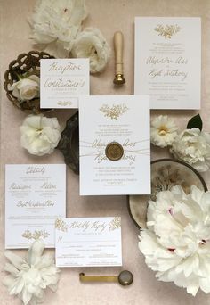 the wedding stationery is laid out on top of the table with white flowers and greenery