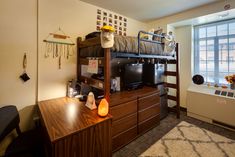 a bedroom with bunk beds and desks in the corner next to a large window