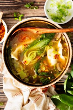 a bowl filled with soup and vegetables next to some chopsticks on a table