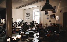 two motorcycles are parked in a room with pictures on the wall and other things around