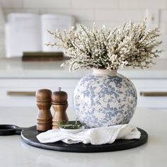 a blue and white vase sitting on top of a counter next to two salt shakers