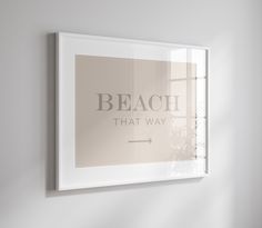 a white frame hanging on the wall above a window that reads, beach that way