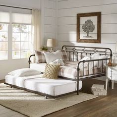 a living room with white walls and wood floors is furnished with an antique style daybed