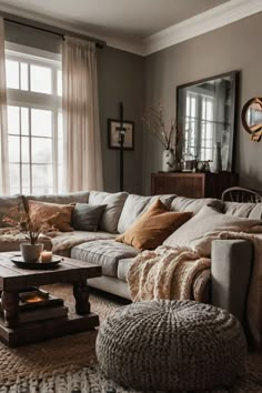 a living room filled with lots of furniture and pillows on top of a rug next to a window