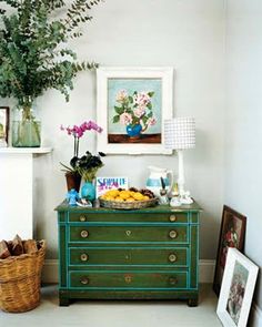 a green dresser with flowers and pictures on it