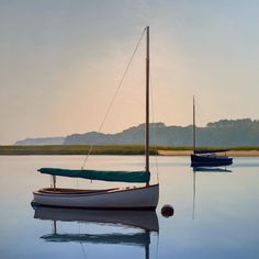 two sailboats floating on the water at sunset