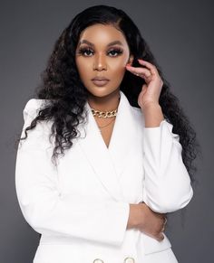 a woman with long hair wearing a white suit and gold jewelry, posing for the camera