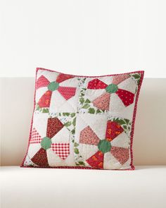 a white couch with a red and green patchwork pillow on it