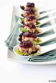 a row of small white plates with food on them and silverware next to each other