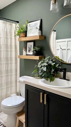 a white toilet sitting next to a sink in a bathroom under a mirror above a wooden shelf