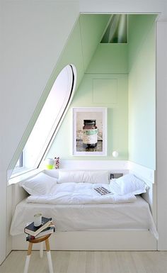 a bed room with a neatly made bed next to a window and a mirror on the wall