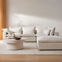 a living room with a large white sectional couch and coffee table in the center area