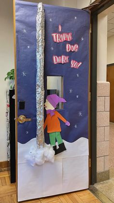 a door decorated to look like a person in the snow with a purple hat and green pants