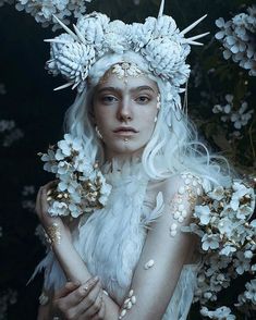 a woman with white hair and flowers on her head is dressed up as a snow queen