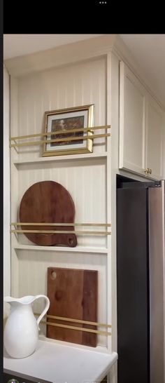 a kitchen with white cabinets and gold trim on the shelves, including a black refrigerator