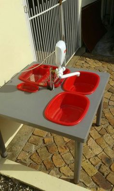 a table with three red bowls on it in front of a white fence and gate