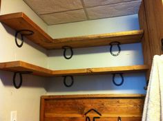 three wooden shelves with hooks on them in a bathroom area next to a towel rack