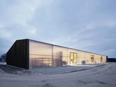 an industrial building with glass doors on the front and side walls is lit up at night