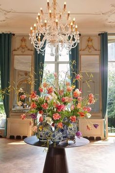 a vase filled with lots of flowers on top of a table next to a chandelier