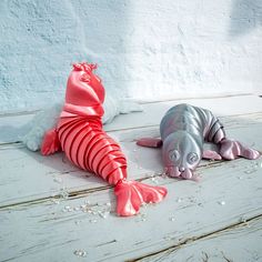 two stuffed animals laying on top of a white wooden floor next to eachother