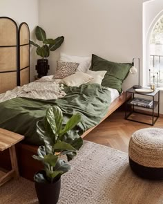 a bed with green sheets and pillows on top of it next to a wooden table