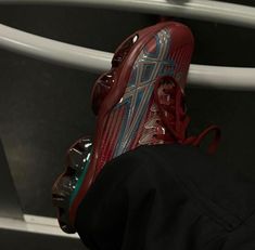 a pair of red and blue shoes sitting on top of a white shelf next to a black shirt