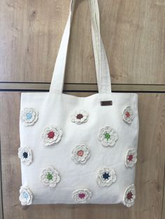 a white bag with flowers on it hanging from a hook in front of a door