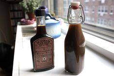 two bottles of syrup sitting on top of a window sill next to each other