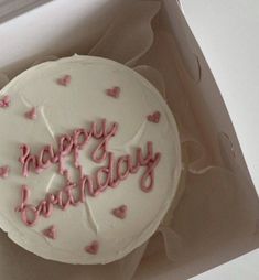 a white birthday cake with pink frosting and hearts on it in a cardboard box