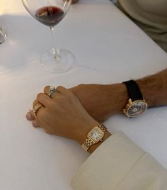 two people are sitting at a table with wine glasses and one is holding the other's hand