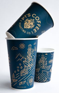 two cups with gold designs on them sitting next to each other in front of a white background