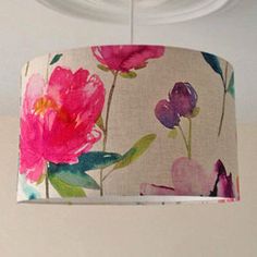 a pink flower print lamp shade hanging from a ceiling fixture in a room with white walls