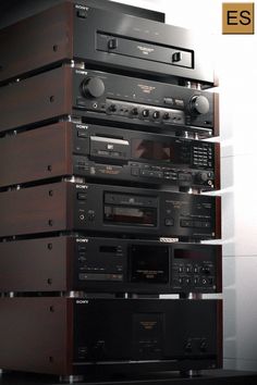 a stack of stereos sitting on top of each other in front of a wall