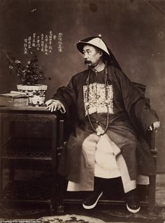 an old photo of a man sitting in front of a table with a potted plant on it