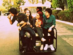 four people sitting on the back of a small cart