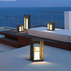 a couple of lights sitting on top of a wooden deck next to the ocean at night