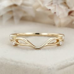 a yellow gold wedding band with three diamonds on the top and bottom, in front of flowers