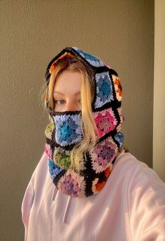 a woman wearing a multicolored crocheted hat and scarf over her face