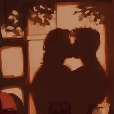 two people are kissing in front of a window