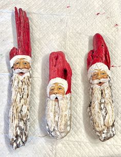 three red and white santa clauss made out of wood