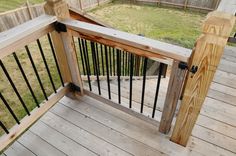 a wooden deck with black iron railings and wood posts on the bottom half of it