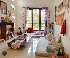 a living room filled with lots of furniture next to a window covered in colorful curtains