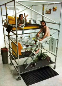 a man and woman sitting on top of a metal bunk bed in a white room