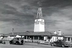 an old black and white photo of a windmill with cars parked in front of it