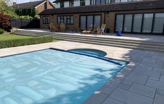 an empty swimming pool with steps leading up to the back door and patio in the background