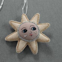 a small star ornament with a face on it's side, hanging from a silver chain