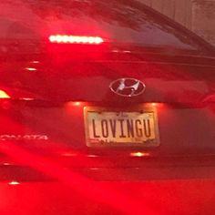 the back end of a red car with a license plate that says loving u on it