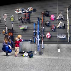 two children are playing with tennis rackets and balls in front of a garage wall