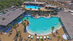 an aerial view of a resort with a swimming pool and cabanas in the background