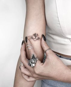 two hands holding each other with tattoos on their fingers and the cat's face